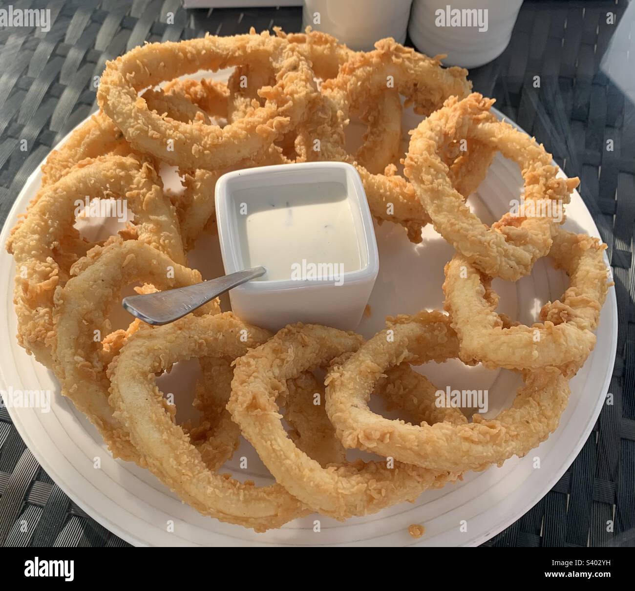 Close up image of a plate of crispy fried calamari rings served with sauce on the side - Smartphone Captured Stock Image