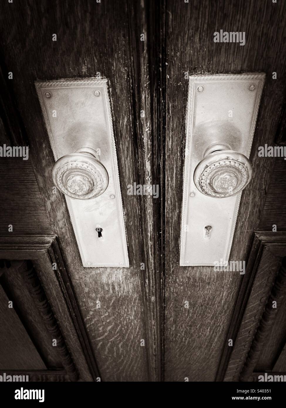 Vintage, metal door knobs on old building in Manhattan, New York. Photo in black-and-white, showing part of wooden doors. - Smartphone Captured Stock Image