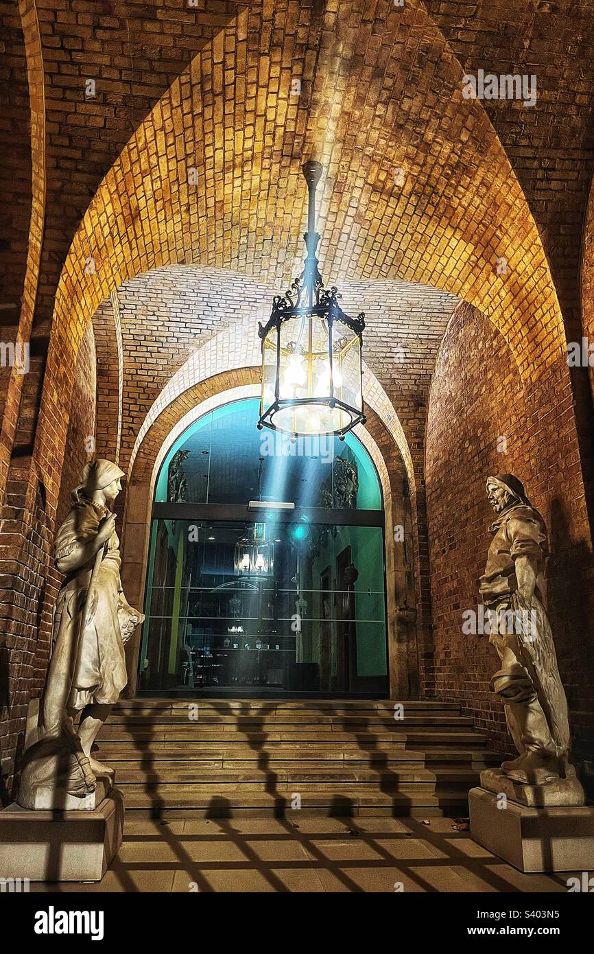 Fishmongers’ Hall from Fishmongers Walk on the Thames Path, London at night entrance showing two statues fisher girl and fisher man in the courtyard - Smartphone Captured Stock Image