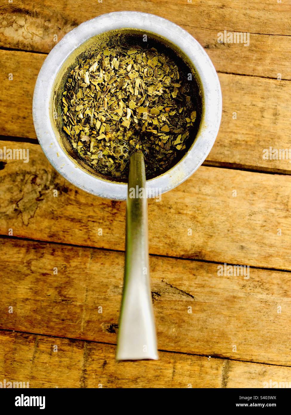Yerba mate leaves with spoon and bombilla on a wooden surface - Smartphone Captured Stock Image