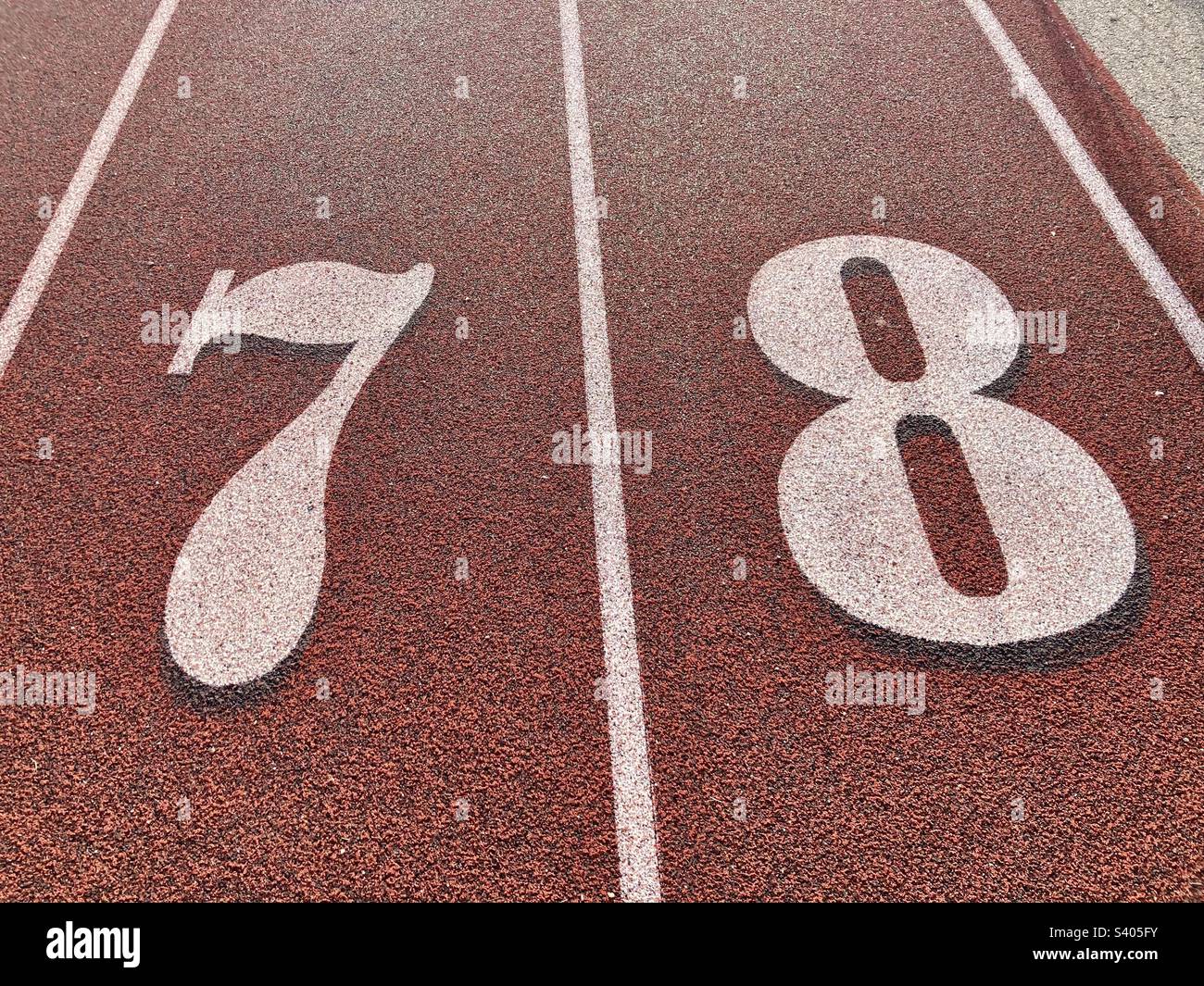Place 7 and 8 on meter line for track and field, with white lettering and red, textured background. - Smartphone Captured Stock Image