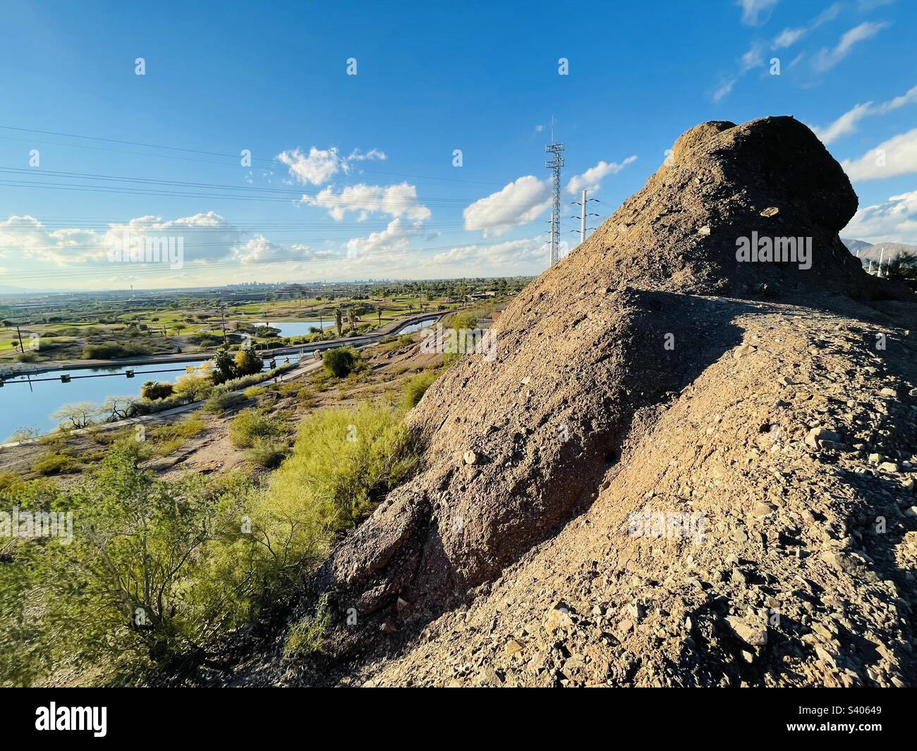 Rocky outcrops overlook green Rolling Hills golf course, Papago Park ponds, Tempe canals. Blue sky with fluffy clouds. Zoom in to see Sky harbor airport control tower, Phoenix AZ downtown skyline Stock Photo
