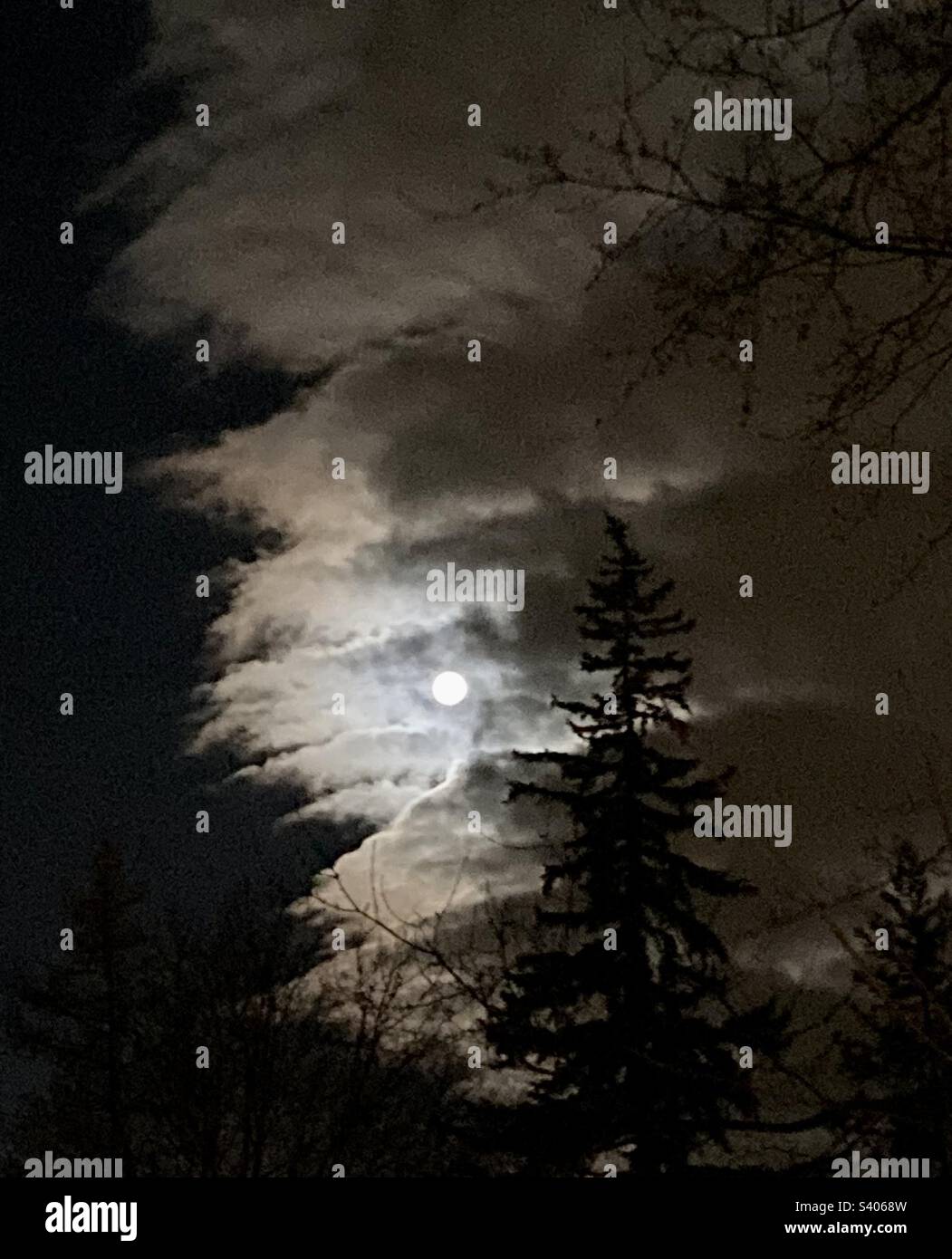 Full moon slipping behind the clouds. - Smartphone Captured Stock Image