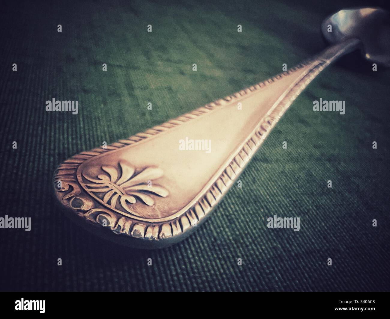 Closeup of a silver spoon against dark green background - Smartphone Captured Stock Image
