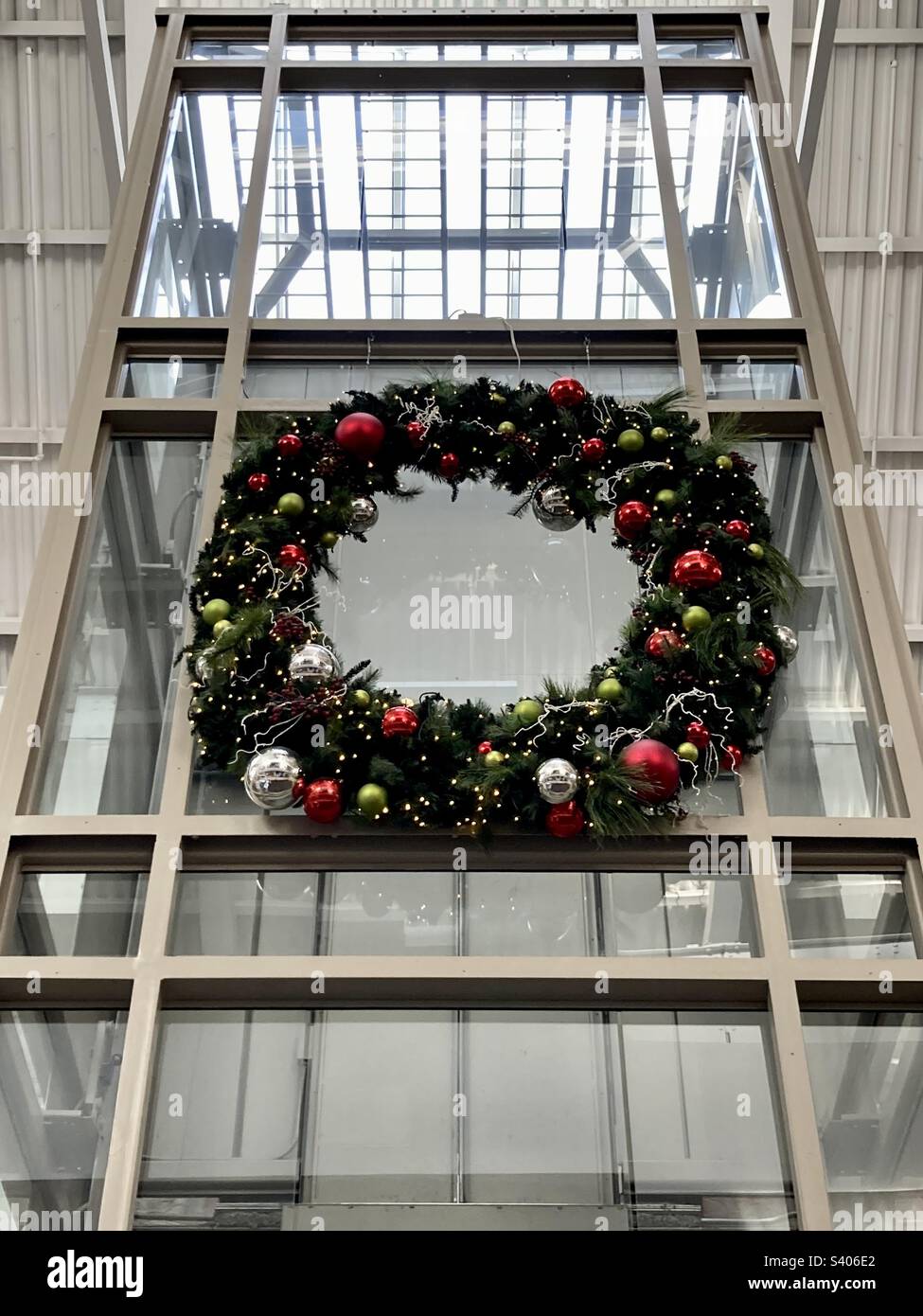 Waterford, Connecticut, USA - December 8, 2022: large holiday wreath hanging on outside of glass elevator in local shopping mall - Smartphone Captured Stock Image