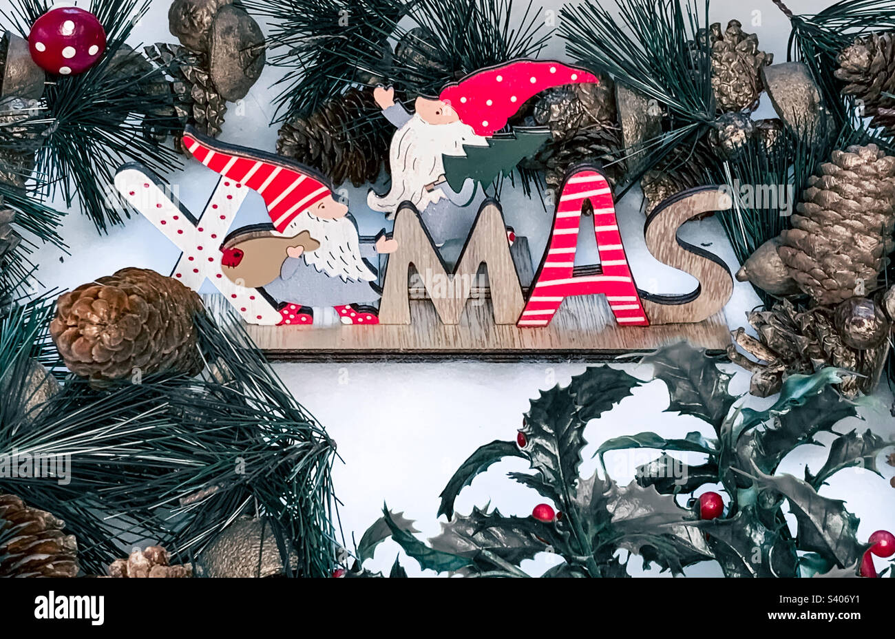 A wooden sign reading Xmas surrounded by a pine cone garland - Smartphone Captured Stock Image