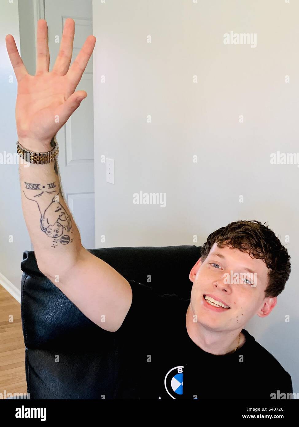Young man with arm up waving to camara - Smartphone Captured Stock Image