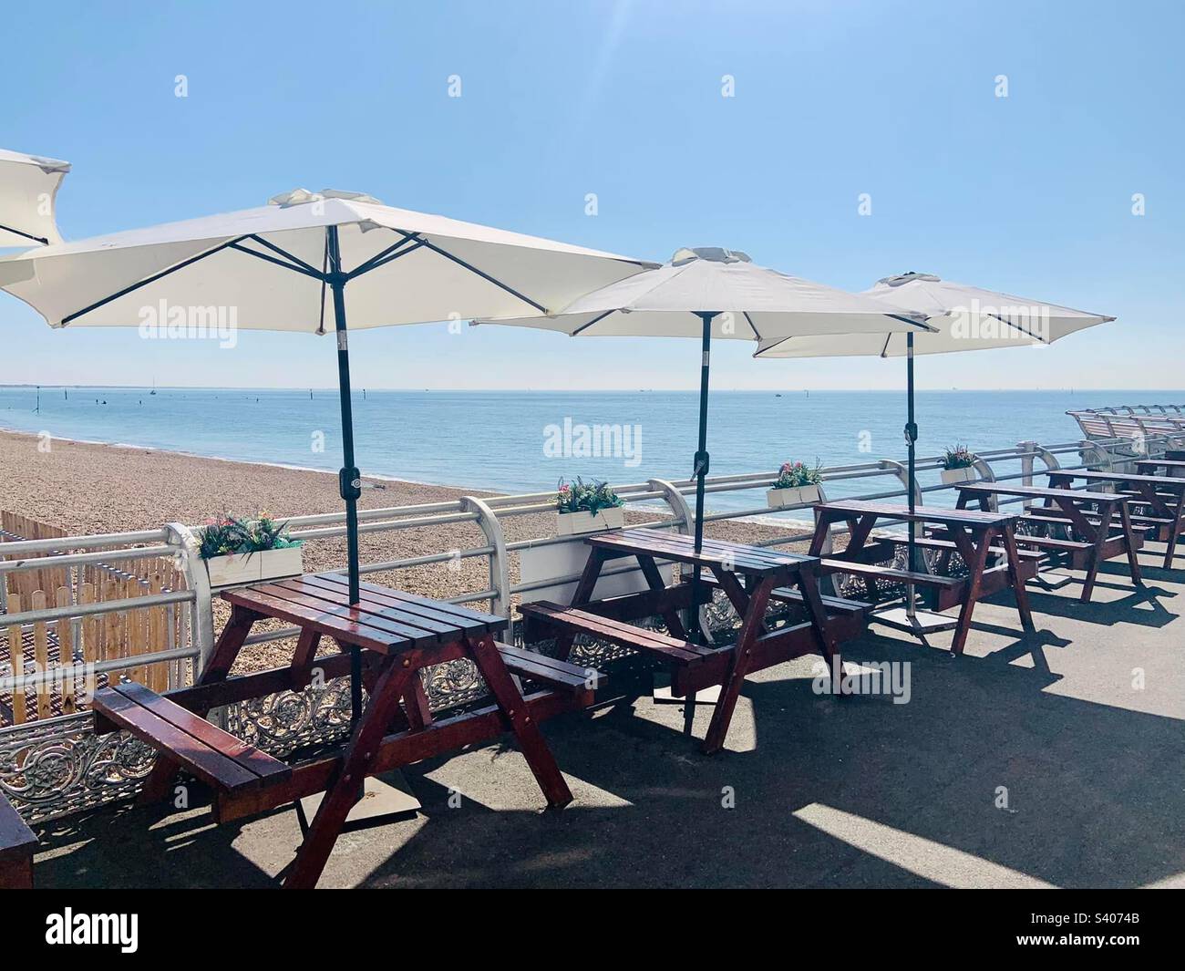 Picnic tables and umbrellas overlooking a beach Stock Photo