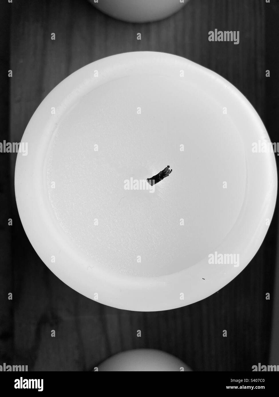 A round white candle with black wick from above - Smartphone Captured Stock Image