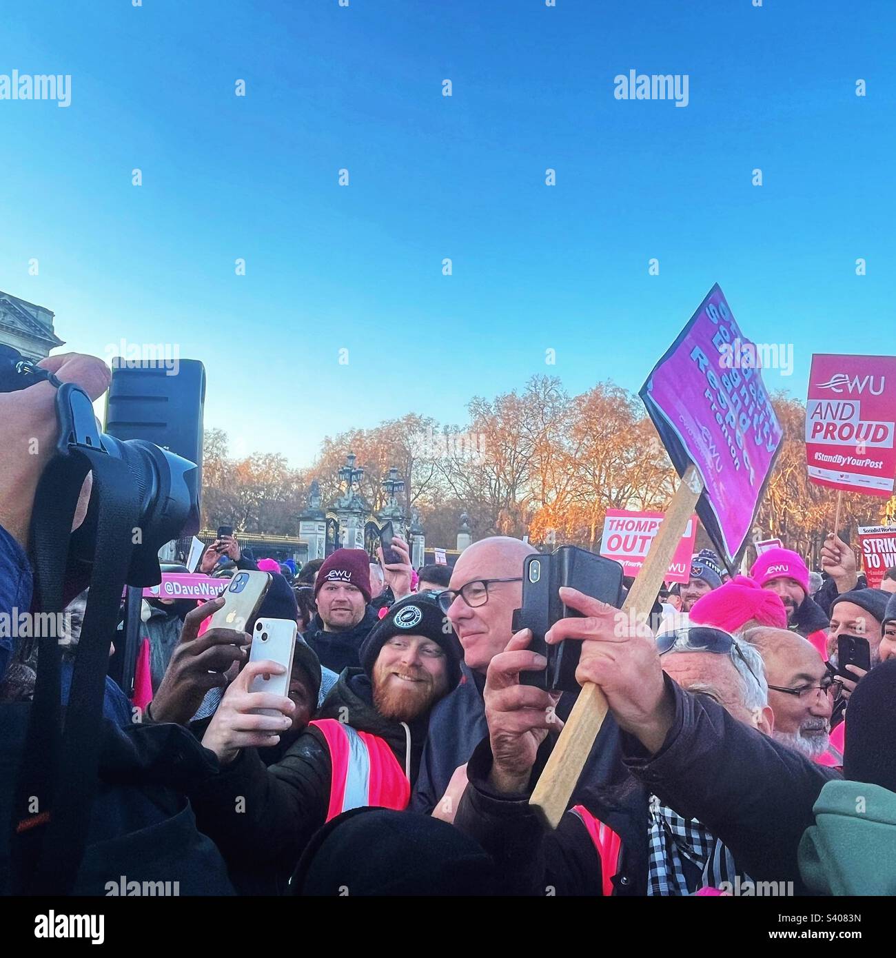 Dave Ward, General Secretary of the Communications Workers Union [CWU] surrounded by postal workers and media with placards on the Mall in London demanding King Charles’s support for his members - Smartphone Captured Stock Image