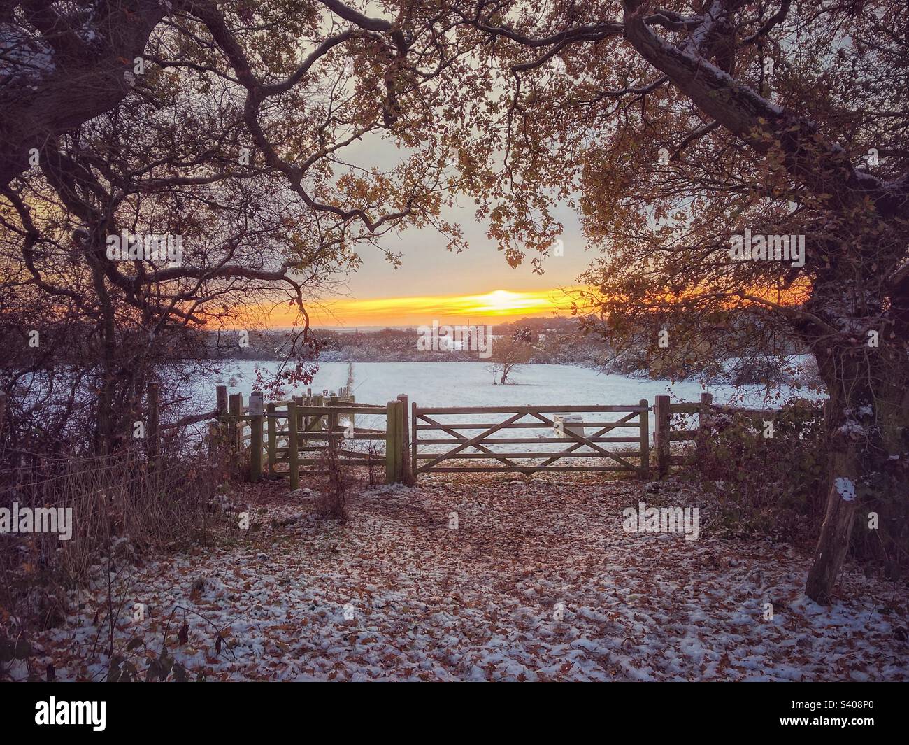 Sunrise over the Essex field gate to a snow covered field with distant views of Kent and the river Thames. - Smartphone Captured Stock Image