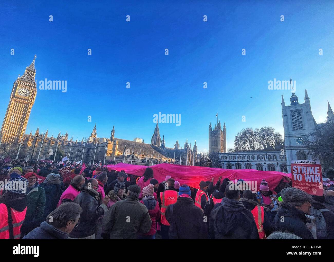 Giant flag being pulled by postal workers at strike rally in Parliament Square London SW1 with Westminster Abbey and Houses of Parliament in background. Trade Union CWU demands fair pay. Dec 2022 - Smartphone Captured Stock Image