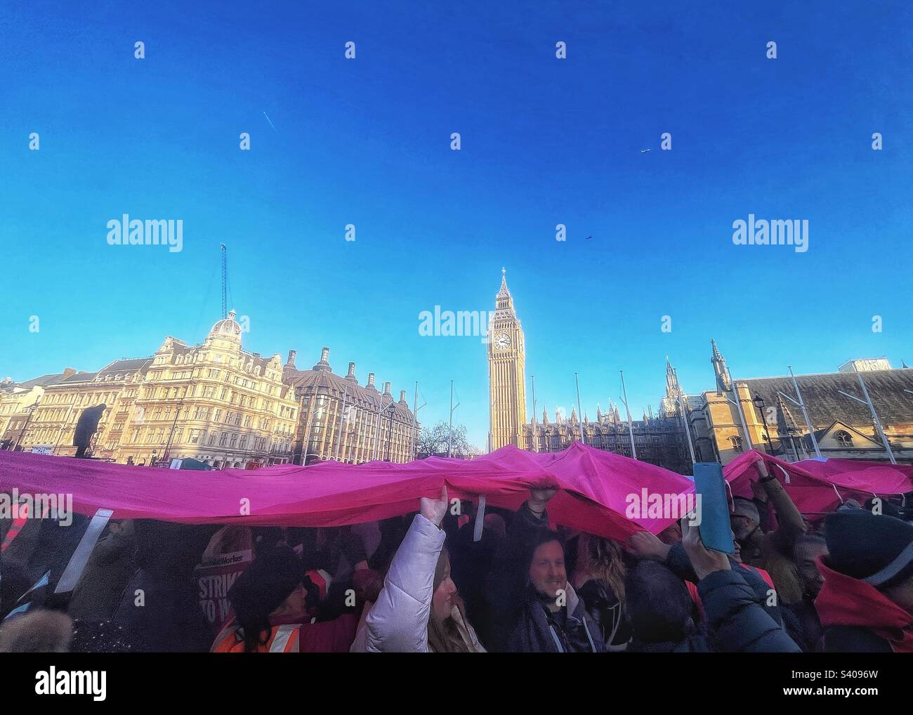 Underneath the giant flag CWU rally in Parliament Square London SW1. The trade unions are calling for an end to austerity with Houses of Parliament in the background - Smartphone Captured Stock Image
