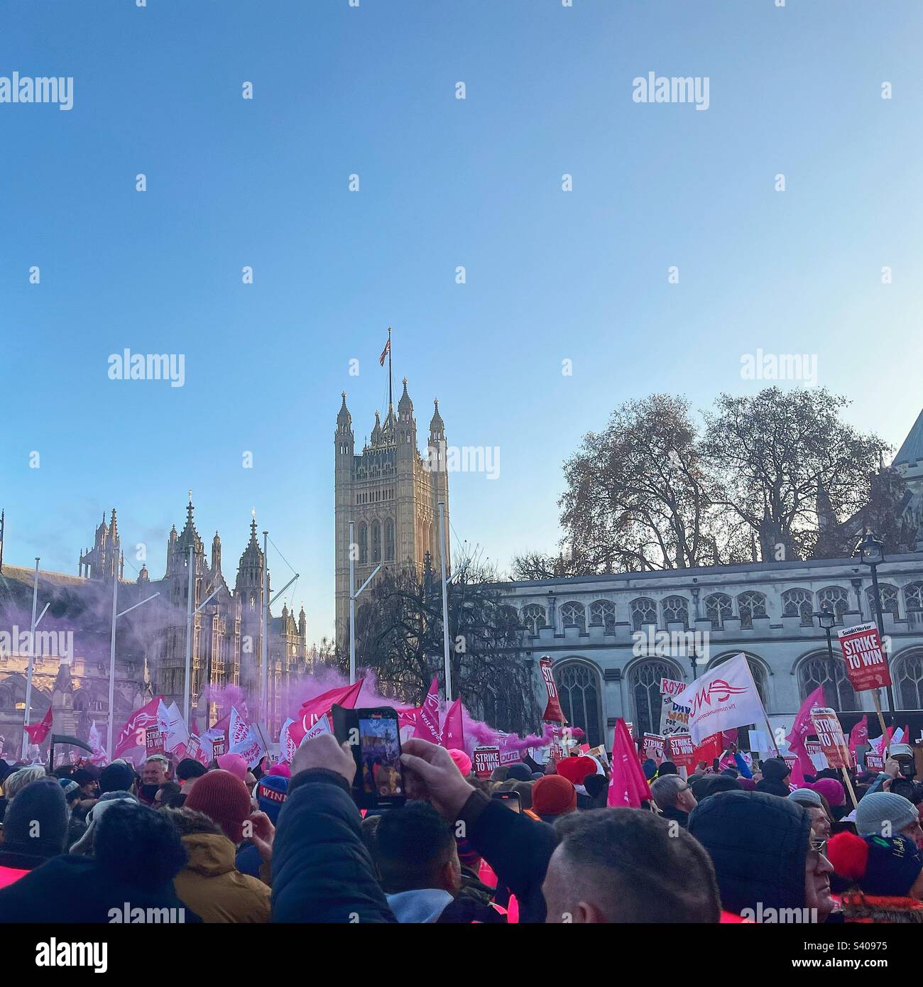Pink smoke drifting across Parliament Square as post workers protest and strike for fair pay. Solidarity with Communications Workers Union members CWU trade union London SW1 - Smartphone Captured Stock Image