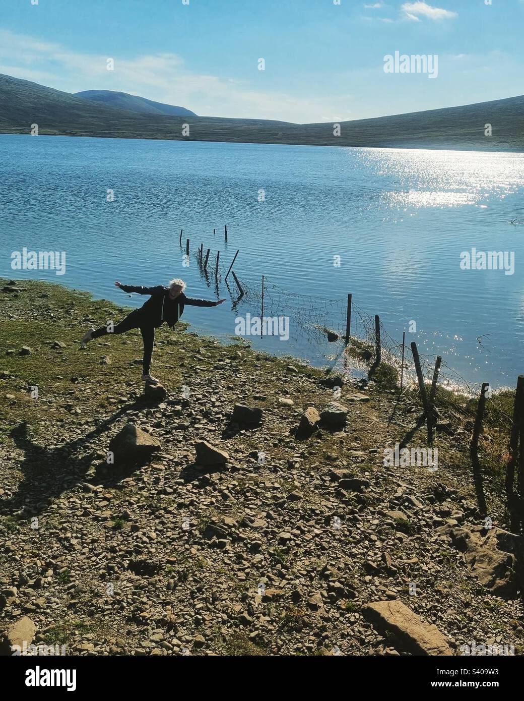 Woman balancing on a rock by a reservoir - Smartphone Captured Stock Image
