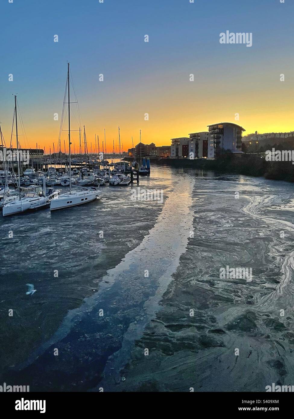 Frozen River Ely running through Penarth marina towards the Cardiff barrage at dawn, December 2022. Stock Photo