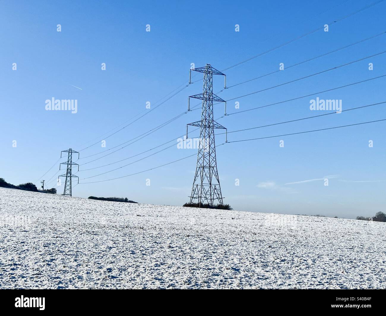 Frozen snow covered fields with electricity pylons on a cold December ...