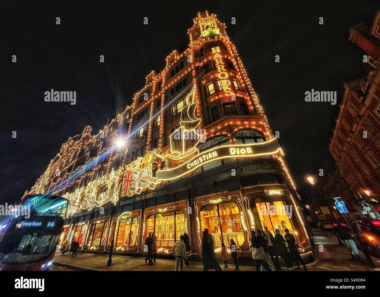 Harrods department store in Knightsbridge London with Christmas lights and a London red bus at night- streets of the city - Smartphone Captured Stock Image