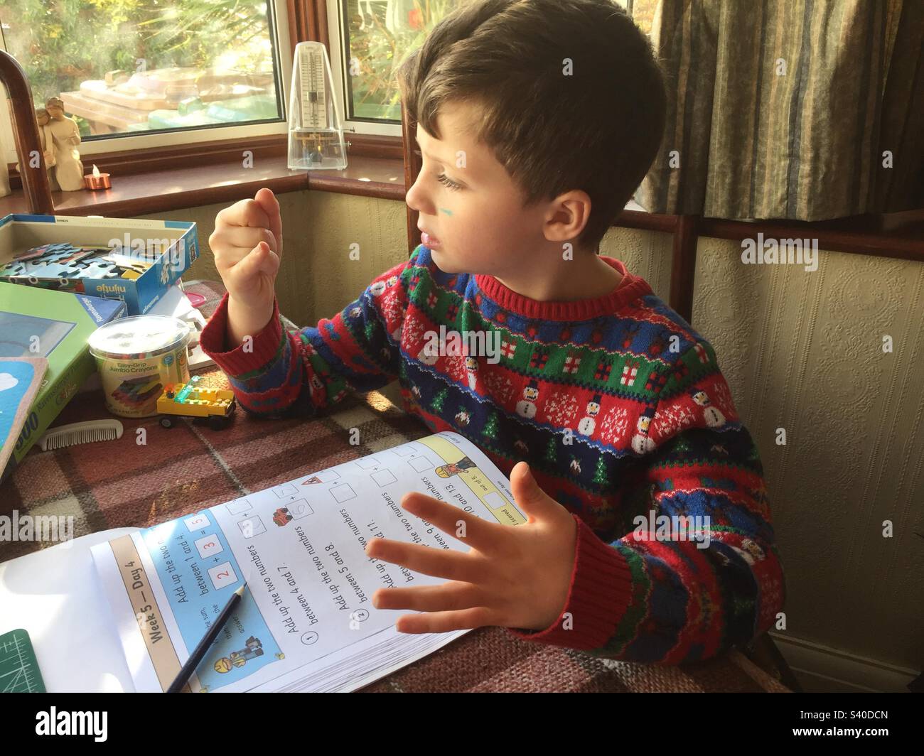 Child doing maths homework and counting on fingers - Smartphone Captured Stock Image