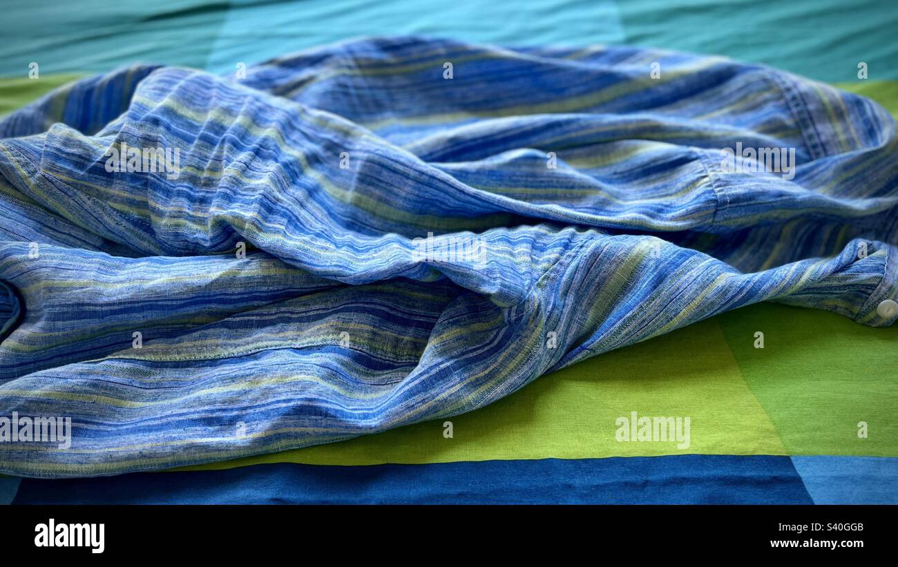 Rumpled blue, green and indigo linen shirt on a blue, green and indigo bed cover, creating abstract image, suitable for graphic background - Smartphone Captured Stock Image