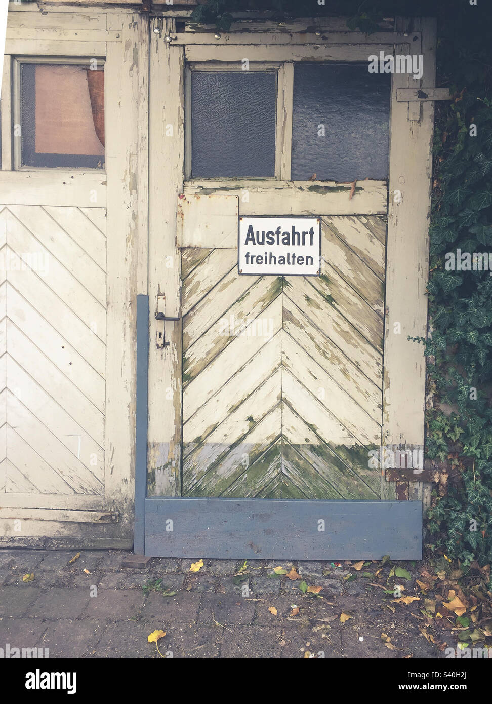 Old wooden door with sign with German text: Ausfahrt freihalten which translates into Keep the exit clear in English language Stock Photo