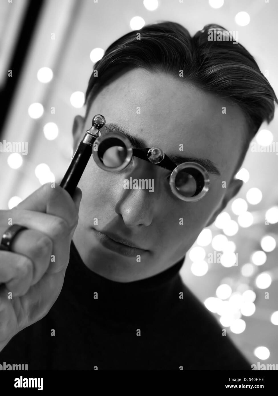 Majestic Man with Theatre Glasses Staring into Camera with Light Bokeh in Background Stock Photo