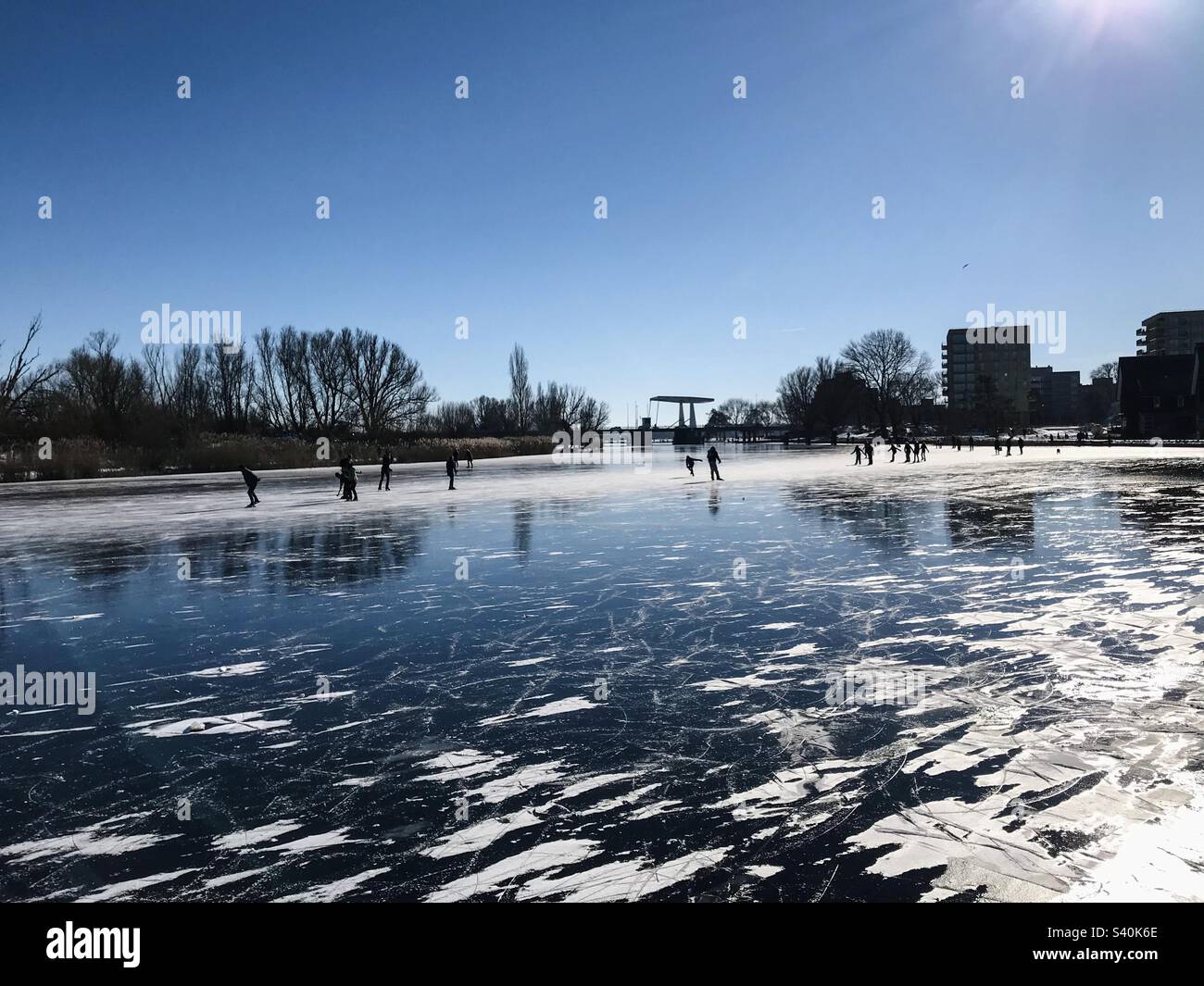People ice skating on a beautiful frozen outdoors big lake in the city - Smartphone Captured Stock Image