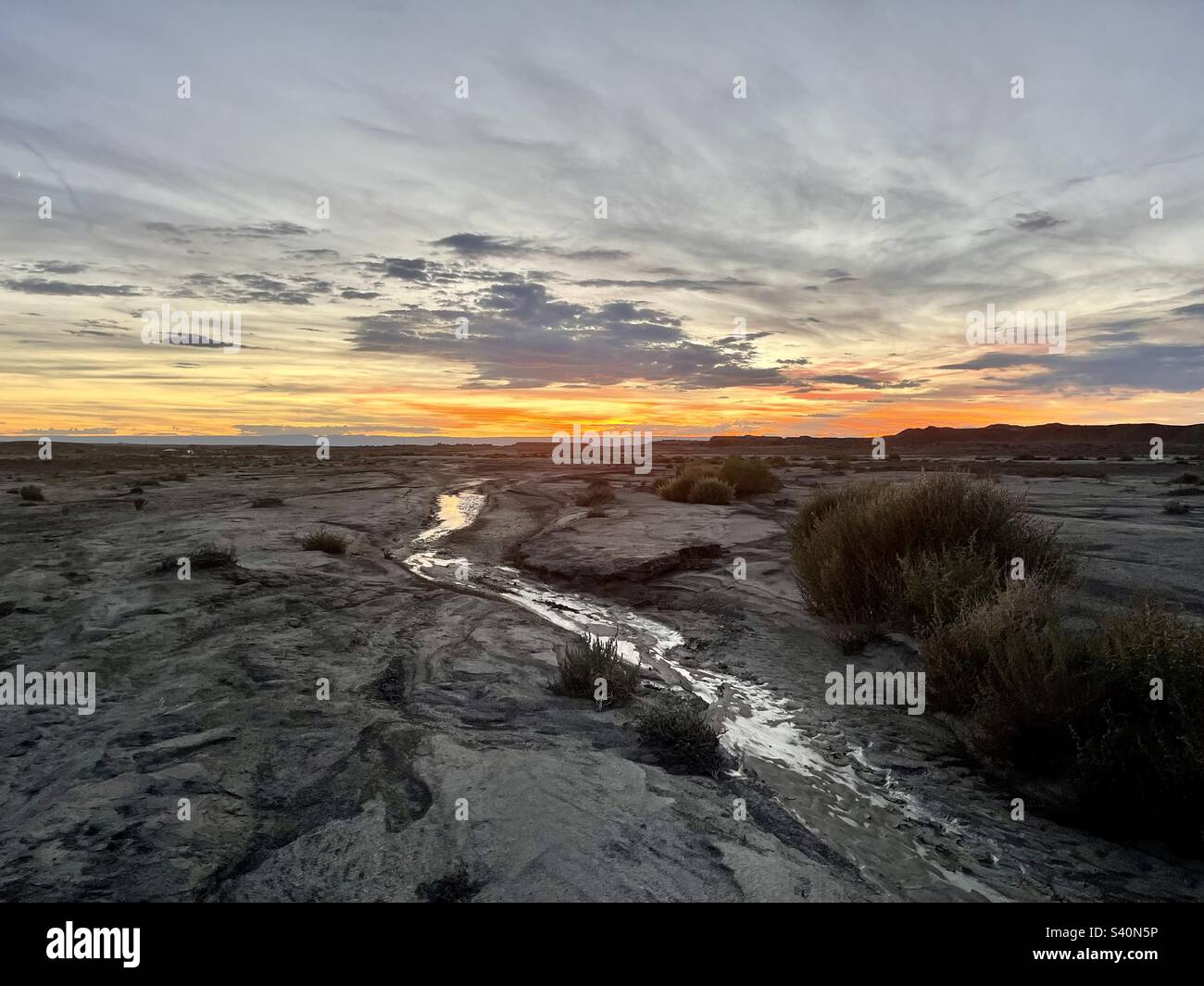An arroyo with a little bit of water running in Bisti / De-Na-Zin Wilderness Area, New Mexico at sunset Stock Photo