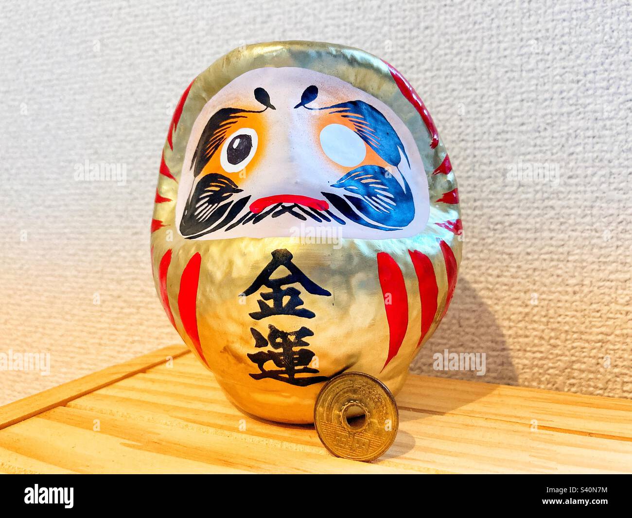 A golden Daruma doll with a 5¥ coin Stock Photo Alamy