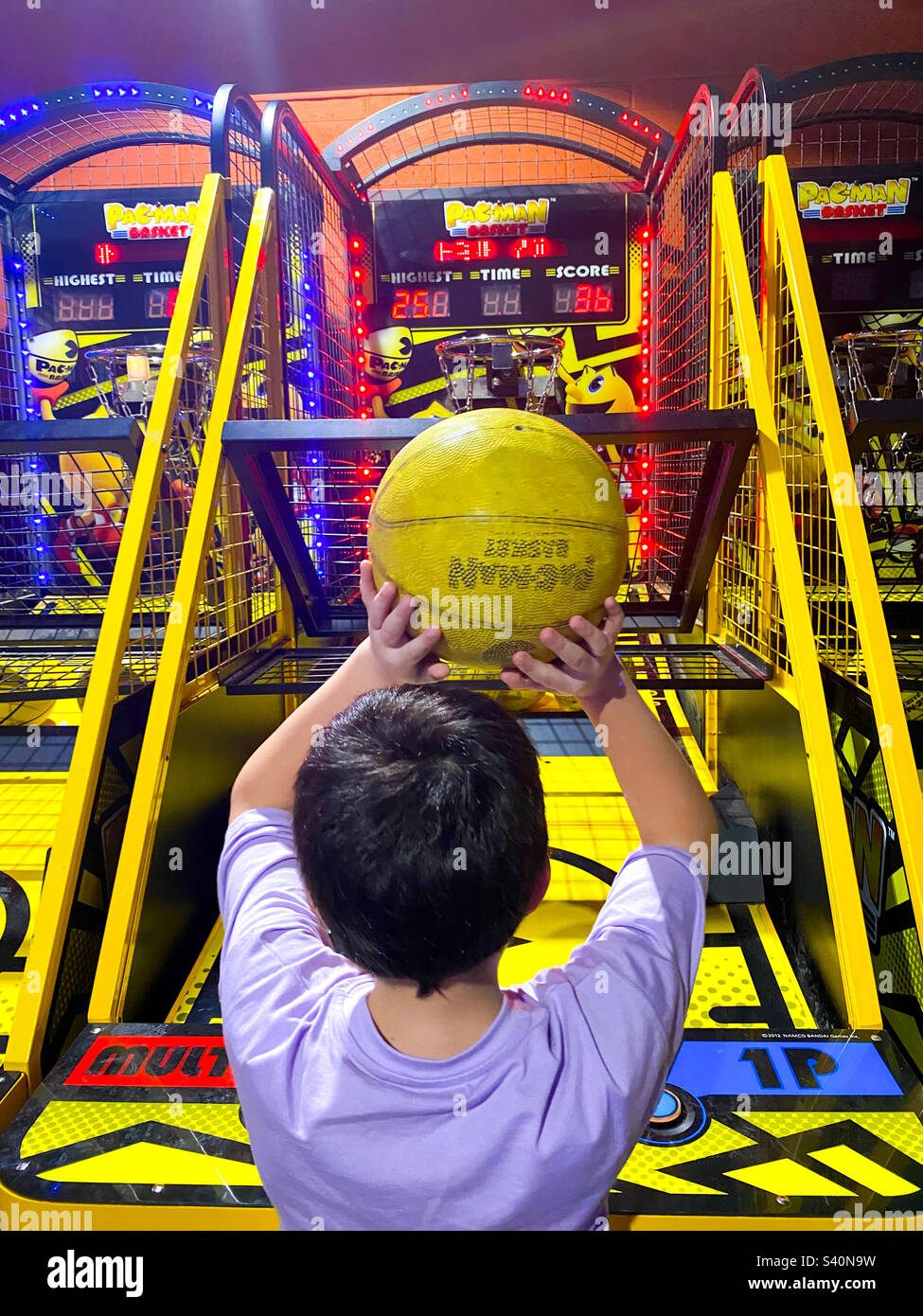A boy playing a basket ball game in an amusement arcade Stock Photo Alamy