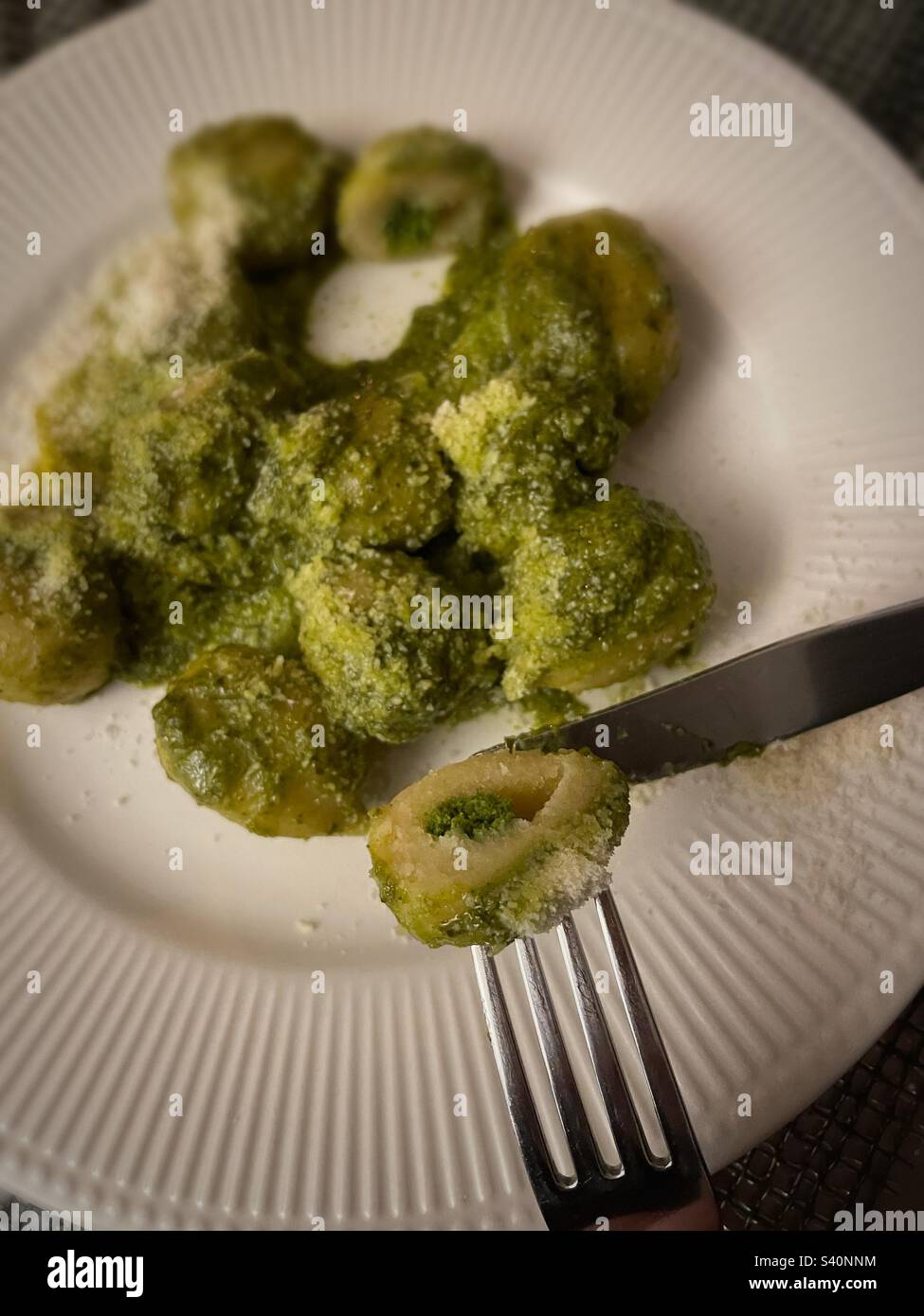 Close up of a diner cutting a pesto flavored gnocchi pasta, 2023, United States - Smartphone Captured Stock Image