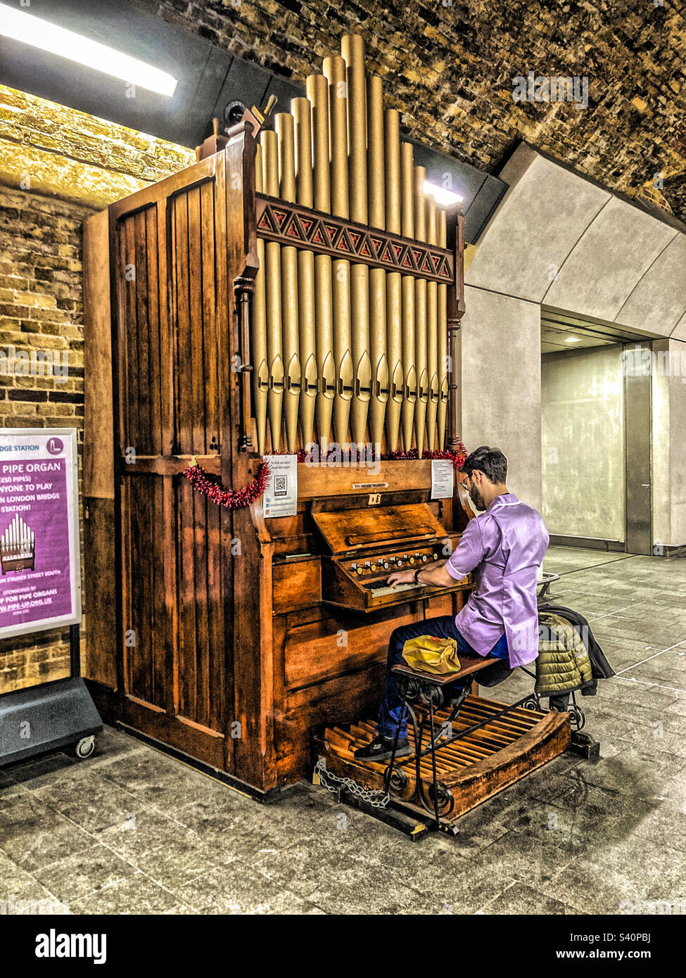 Male nurse playing a pipe  organ at London Bridge Railway Station in the Stainer Street concourse - Smartphone Captured Stock Image