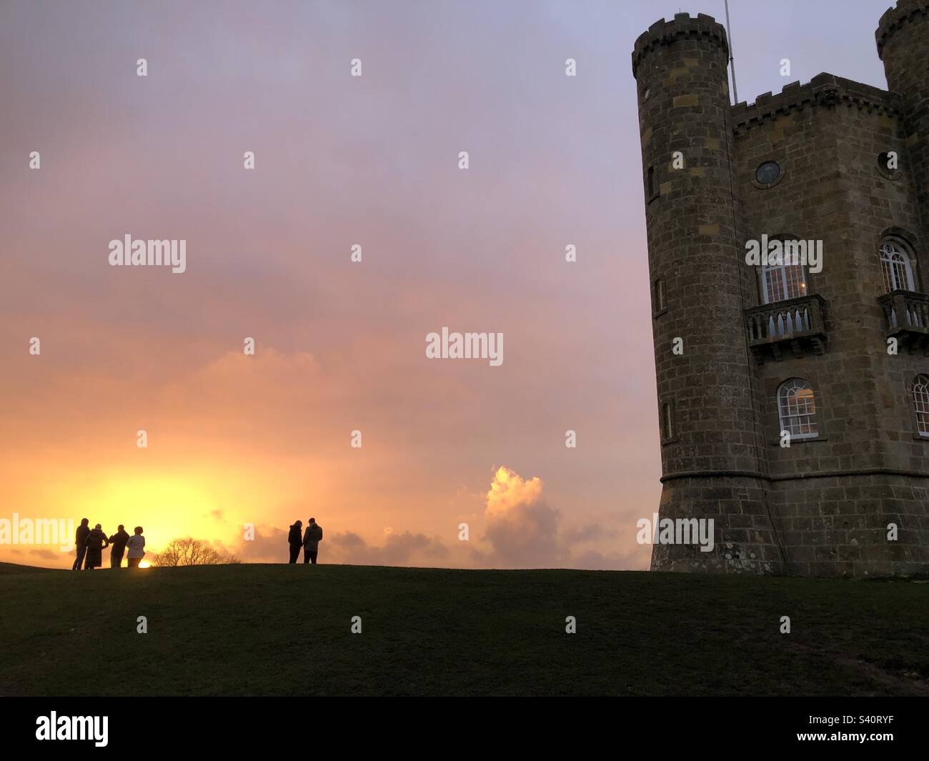 Broadway Hill Tower with two groups of people on the skyline backed by a glowing red sunset. - Smartphone Captured Stock Image