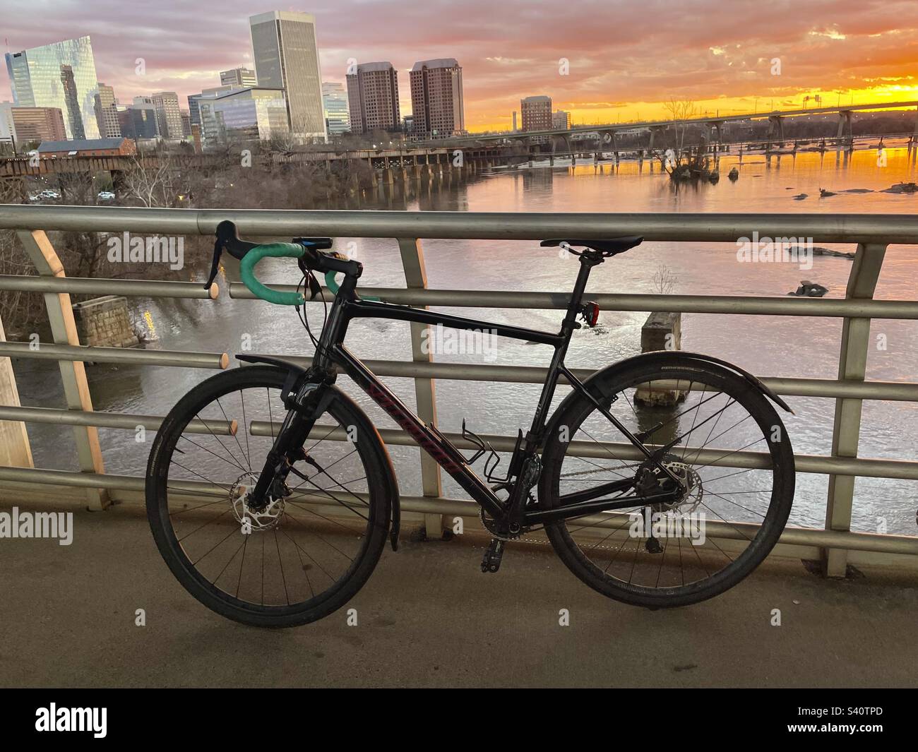 A gravel bike sits along a bridge railing in front of a waterfront cityscape in Virginia. Stock Photo