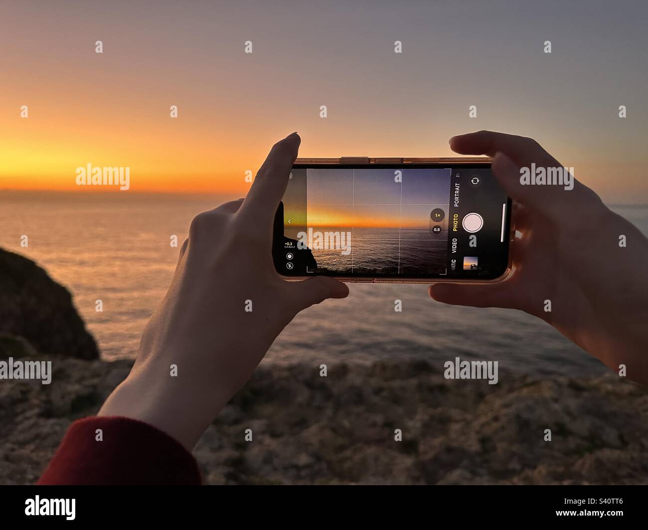 Hands holding mobile phone while taking photo of sunset - Smartphone Captured Stock Image