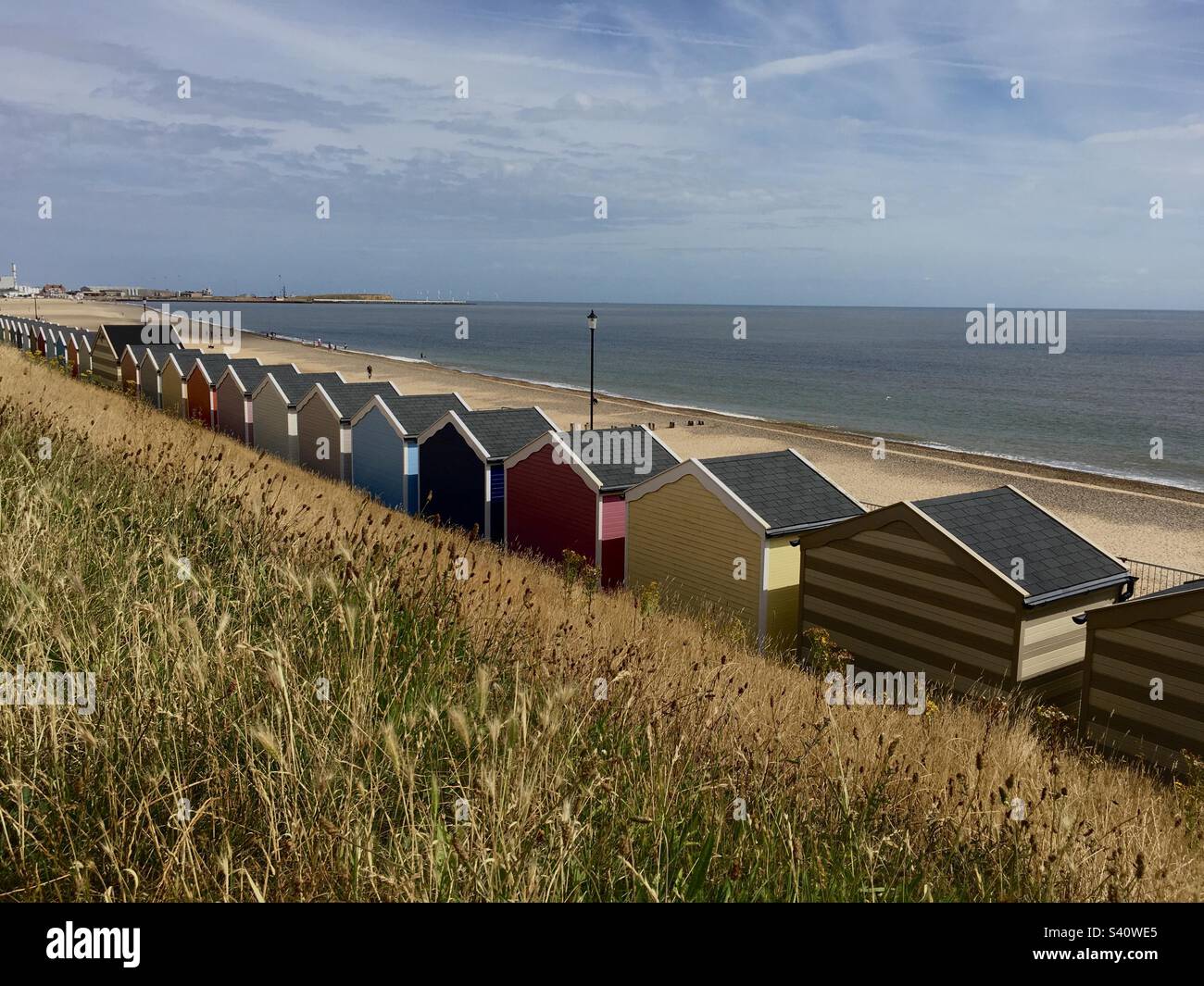 Beach huts on promenade, roll of summer huts facing the North Sea, grass on foreground, colourful huts, Gorleston on Sea, Norfolk, UK - Smartphone Captured Stock Image