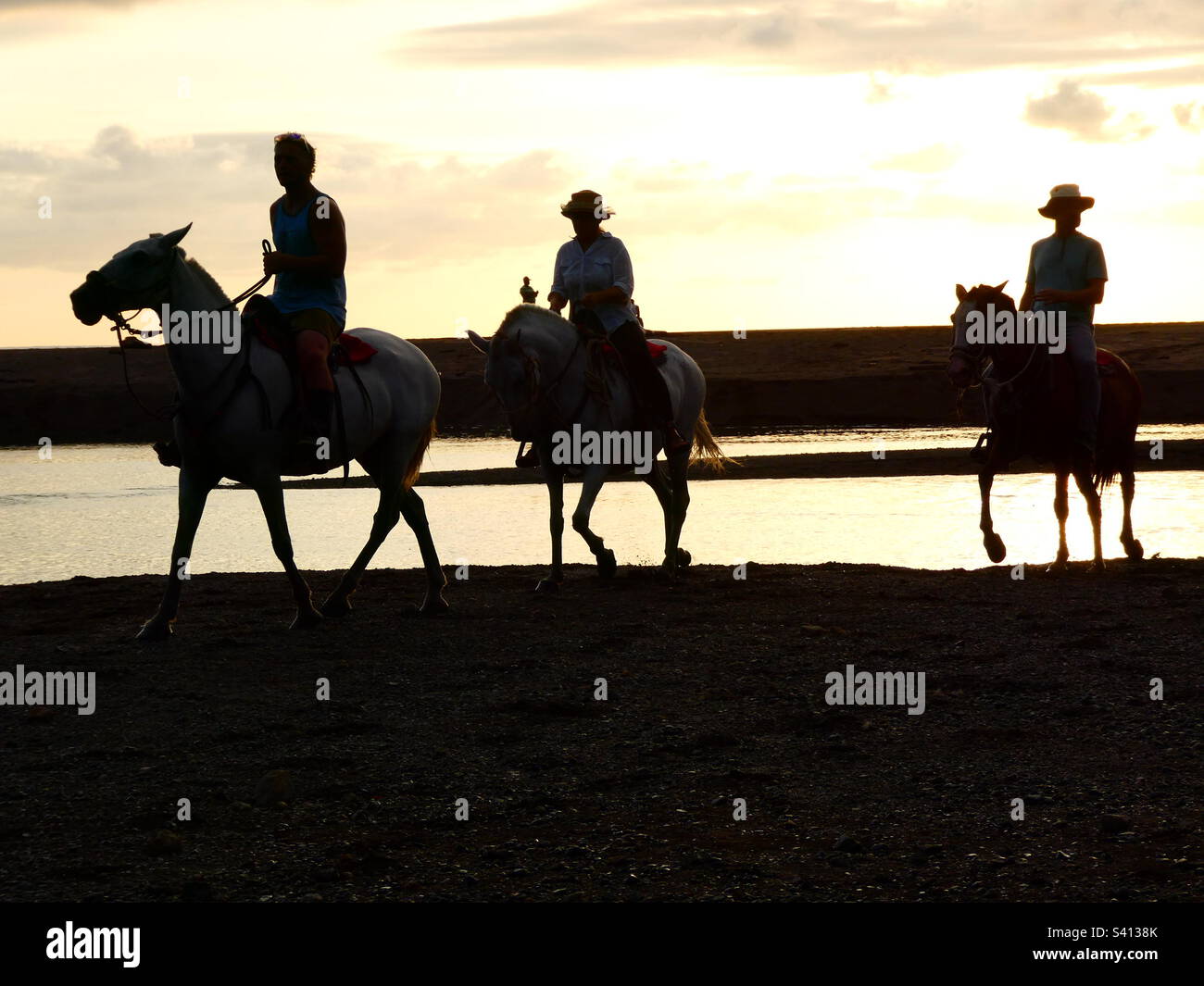 Three horse riders riding along near the beach at sunset in Samara Costa Rica - Smartphone Captured Stock Image