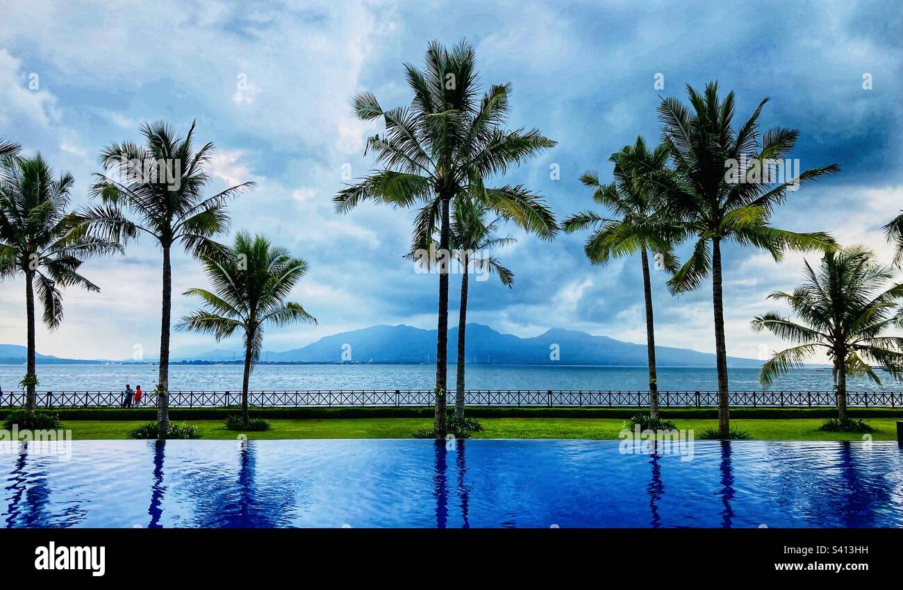 View of swimming pool palm trees and then across the Bali strait to Bali from Banyuwangi Indonesia - Smartphone Captured Stock Image
