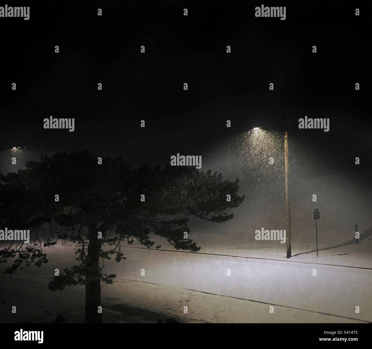 Snow falling in cones of light under streetlights on a quiet winter night - Smartphone Captured Stock Image