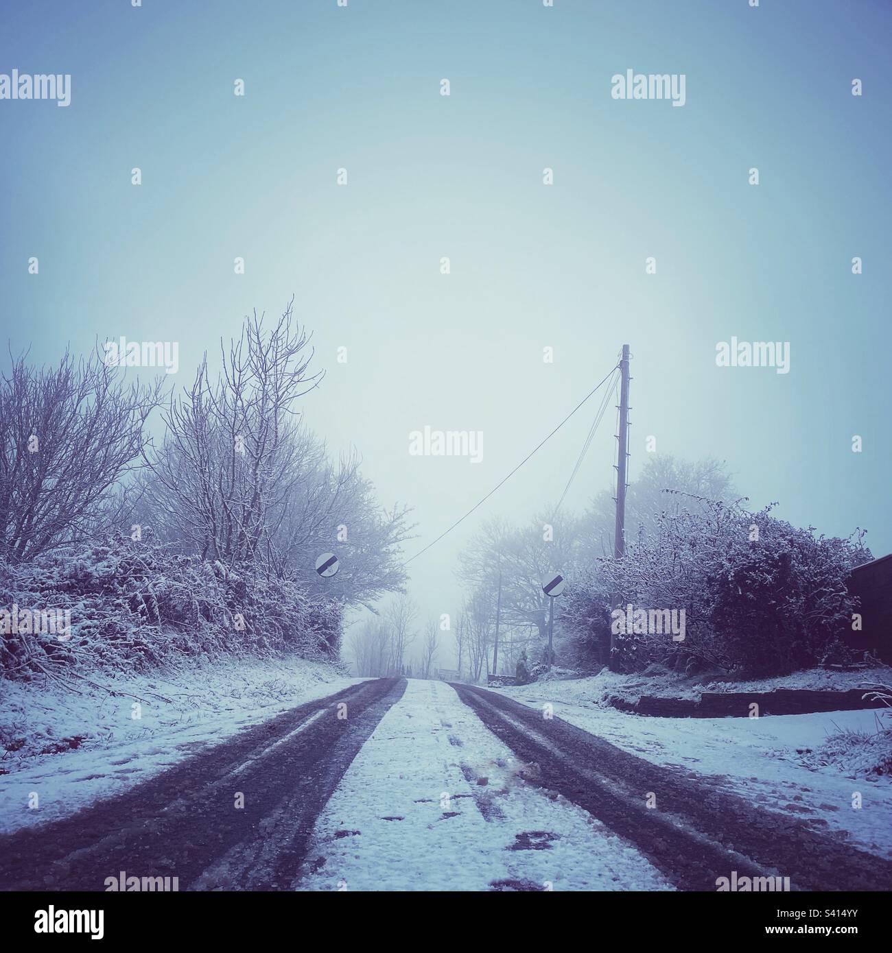A photograph of a snowy country lane with national speed limit signage. - Smartphone Captured Stock Image