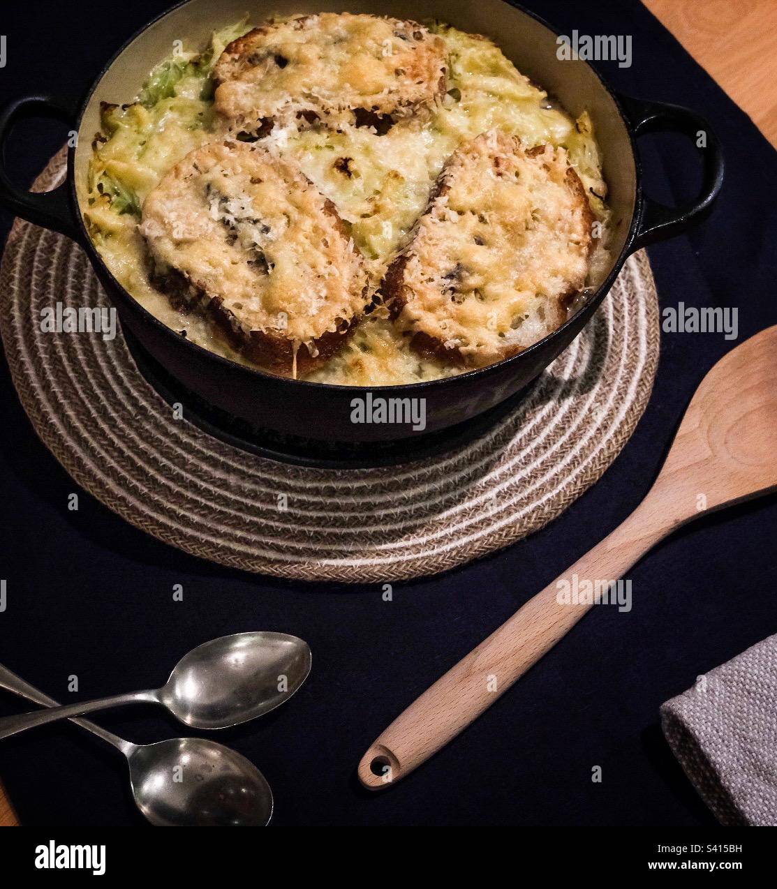 A hearty dish of Zuppa d’Aosta being served on a table with spoons and napkins Stock Photo