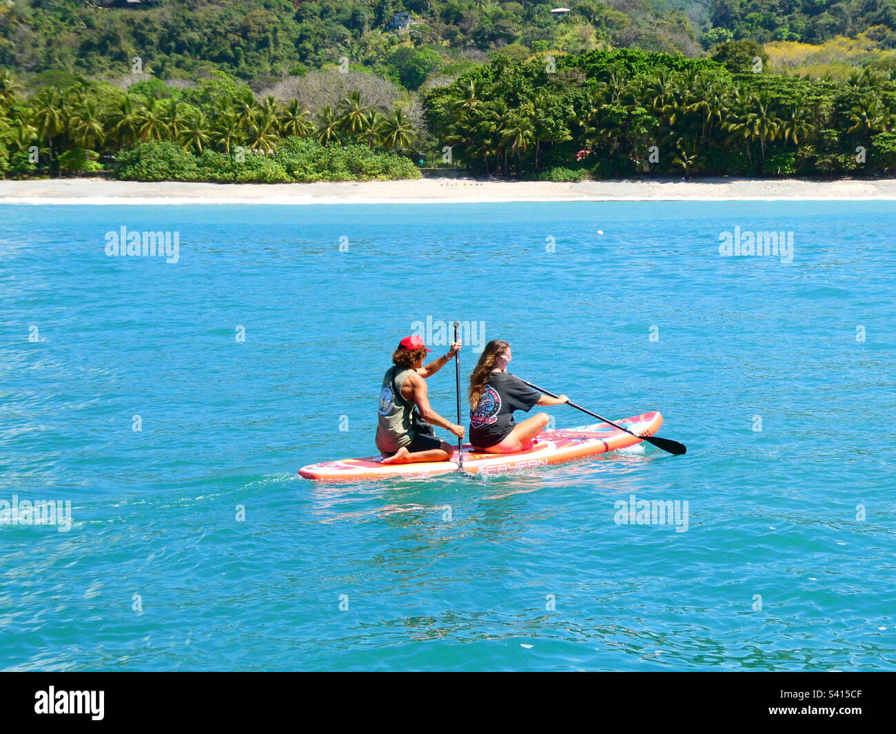 Two people paddling on a paddle board on calm water in Costa Rica - Smartphone Captured Stock Image