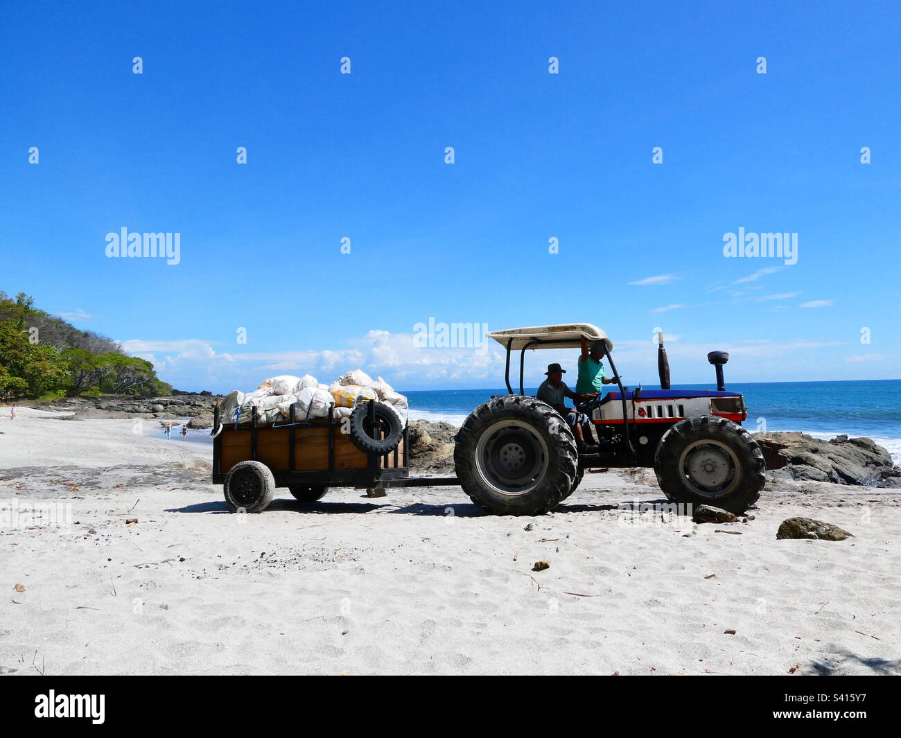 A tractor takes bags of waste along the beach for recycling in Costa Rica - Smartphone Captured Stock Image