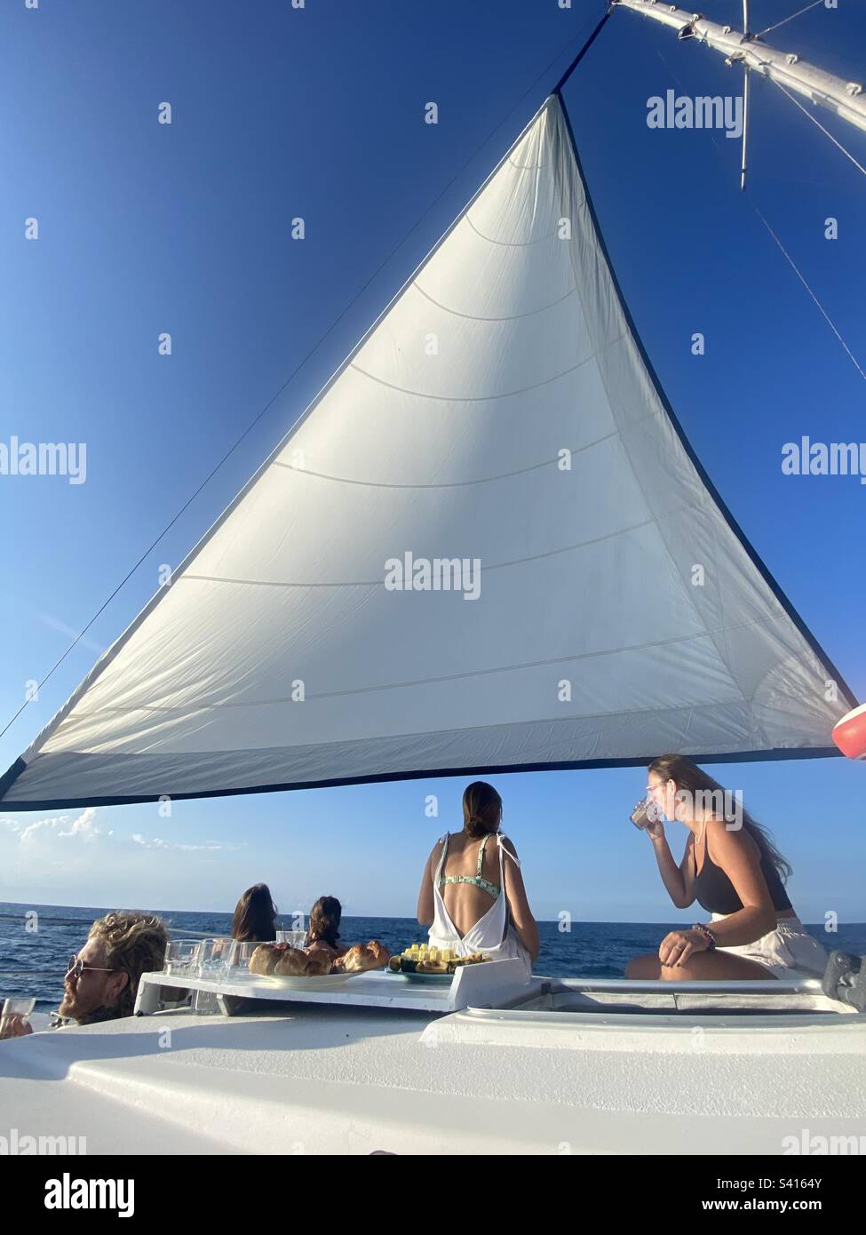 People relax and drink under the sails of a catamaran boat off the coast of Costa Rica - Smartphone Captured Stock Image