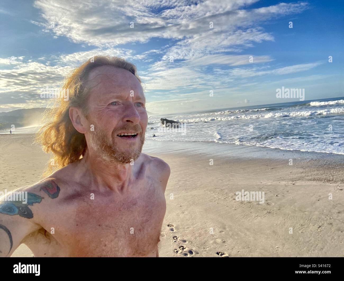 A man takes a morning run on the beach on a sunny day in Santa Teressa in Costa Rica - Smartphone Captured Stock Image