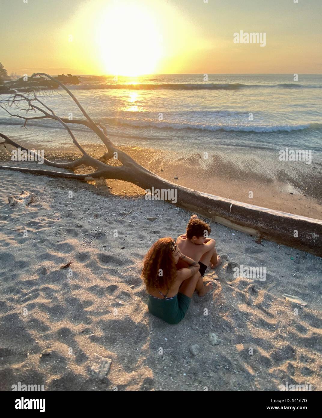 A young couple enjoy the sunset from a beach in Santa Teressa in Costa Rica - Smartphone Captured Stock Image
