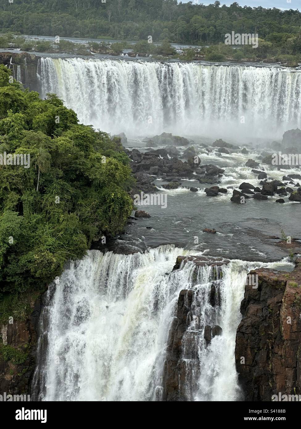Half cloudy and blue day despite everything, a green forest around and in the background of the image some of the various waterfalls of the Iguaçu river falls in Foz do Iguaçu-Brazil Stock Photo