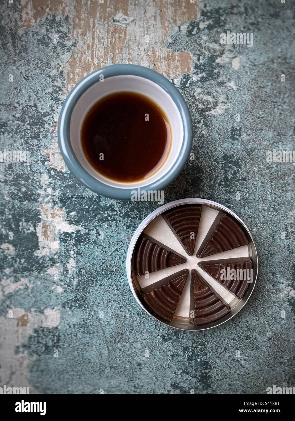Cup of black coffee and a tin of chocolate triangles - Smartphone Captured Stock Image