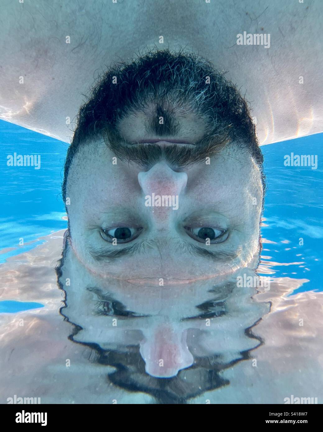 Abstract underwater photo of bearded man in swimming pool. - Smartphone Captured Stock Image