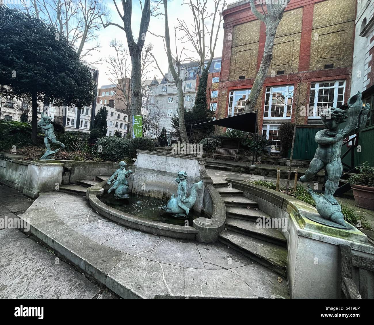 St James’s Church in Piccadilly a fountain was executed by Masons to the design of Alfred  Hardiman RA. The stone fountain with cherubs, dolpins and a elliptical stone basin flanked by steps - Listed - Smartphone Captured Stock Image